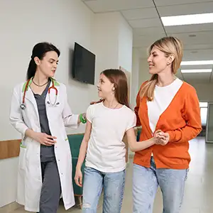 Doctora dirigiendo a una paciente y su madre hacia el estudio clínico