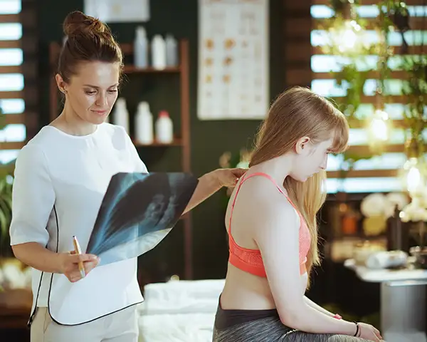 Doctora analizando si su paciente sufre escoliosis